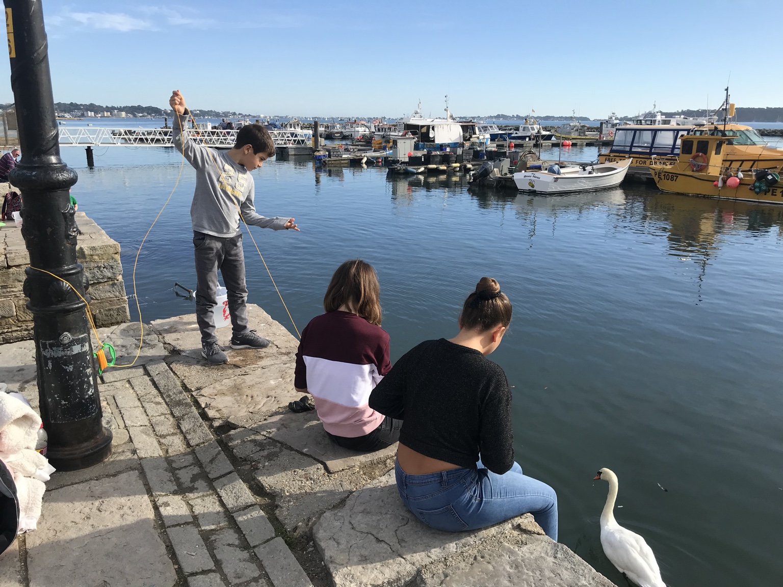 Children crabbing beside fishing boats on Poole Quay