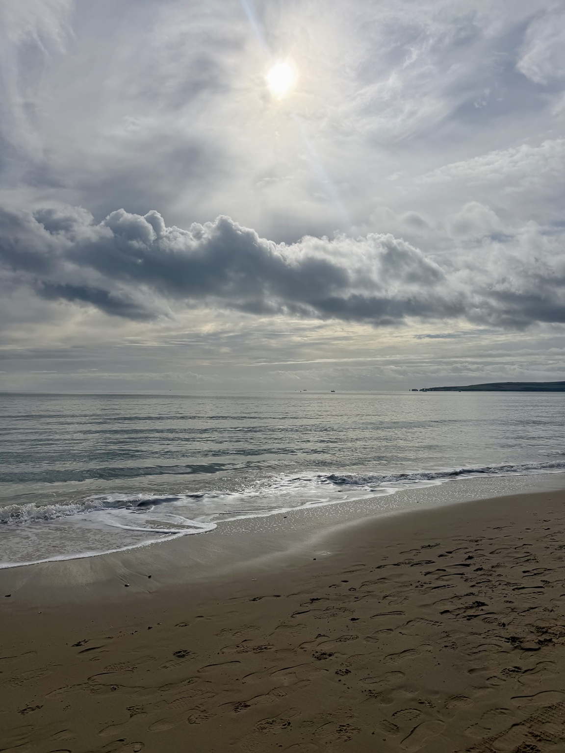 Sunlight breaking through clouds above a quiet beach and sea