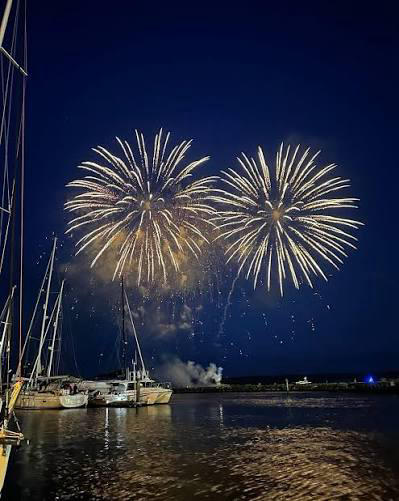 Golden fireworks above the harbour, with yachts and reflections on the water