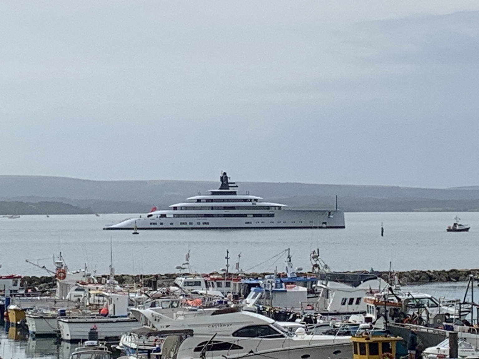 A large yacht beyond the fishing boats in Poole Harbour