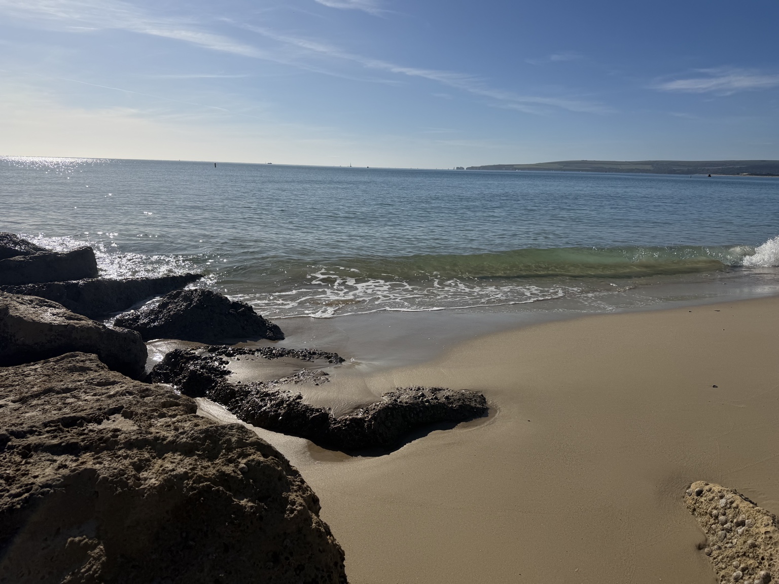 Clear sea and a sandy beach beside a rocky groyne